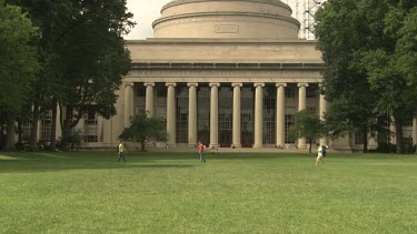 People on the lawn behind an MIT building with grand columns