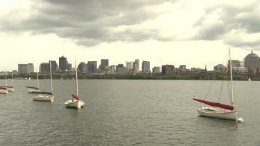 Sailboats in the water outside a city on a cloudy day