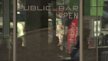 Pedestrians reflected in the glass window of a bar