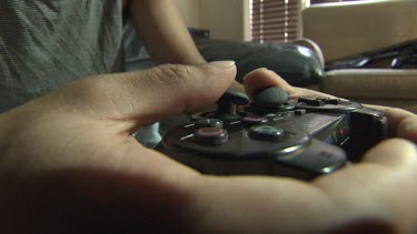 Close up of a person playing on a Playstation controller