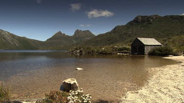 Rocky mountains and a wooden shelter at the edge of a lake