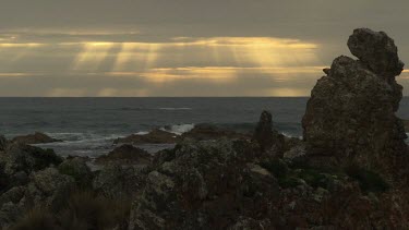 Waves breaking against a rocky shore at sunset