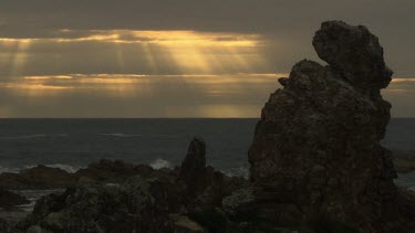 Waves breaking against a rocky shore at sunset