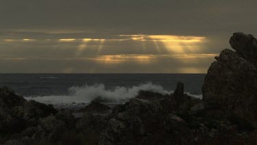 Waves breaking against a rocky shore at sunset