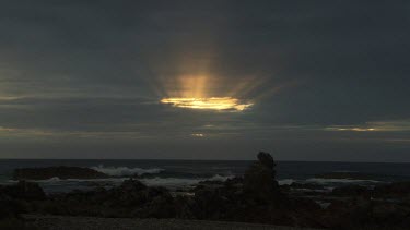 Waves breaking against a rocky shore at sunset