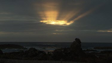 Waves breaking against a rocky shore at sunset