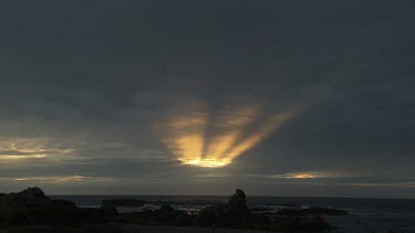 Waves breaking against a rocky shore at sunset