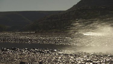 Truck driving through a shallow, rocky stream