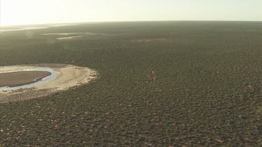 Round, sandy island surrounded by desert vegetation