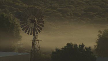 Morning fog over a wooden windmill