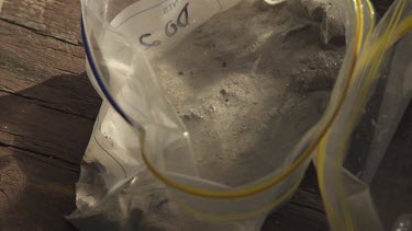 Injecting a syringe into grey mud in a plastic bag