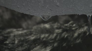 Close up of water flowing in a stream with snow dripping overhead