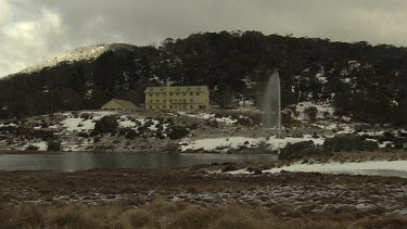 Fountain spraying water by a building in snowy mountains