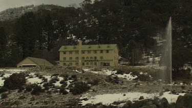 Fountain spraying water by a building in snowy mountains