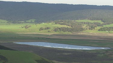 Blue lagoon banked by rolling green hills in Great Otway National Park