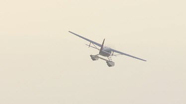 Seaplane flying against a cloudy grey sky