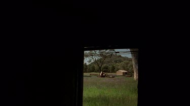 Hut and old farm machinery, shot thru. Window