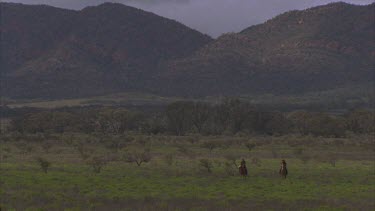 horse riders ride towards camera salvation Jane in flower and ranges in background