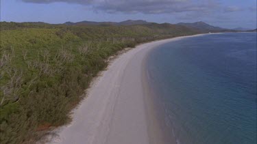 aerials of Whitsunday island pass low Whitehaven beach along white sands fringed by ocean and forest **