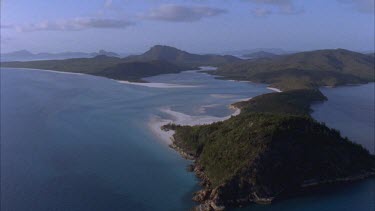 aerials of Whitsunday islands vegetated and fringed by white sands and ocean travel up inlet with mangroves