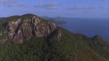 aerials of Whitsunday island with large rock outcrop and over to other rocky bays Mountain ?