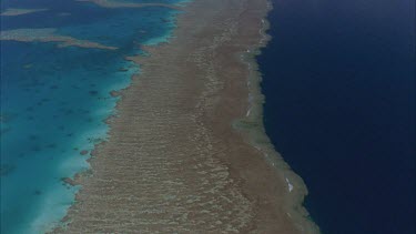 tracking shots over the great barrier reef showing reef waters one side pale blue and deep blue of outer ocean on other then isolated coral cays