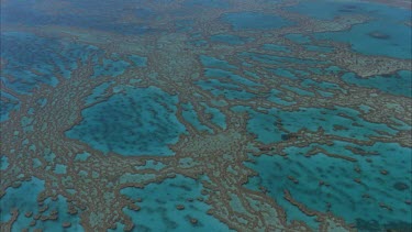 tracking shots over the great barrier reef a mosaic of small reefs with blue water between isolated coral cays traveling over different shades of blue**