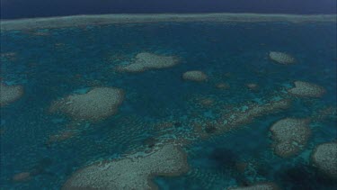 tracking shots over the great barrier reef showing reef waters a mosaic of small reefs with blue water between isolated coral cays **