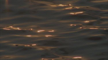 sunlight late afternoon reflecting on water surface, gently undulating waves , various in and out of focus effects