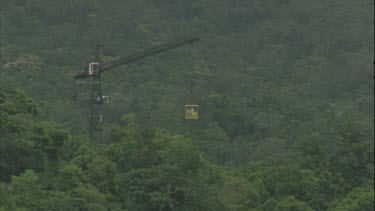 canopy crane bucket suspended out over forest and swinging around