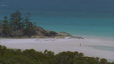 WS of Whitehaven beach with contrasting white sands and blue clear water person walks to waters edge