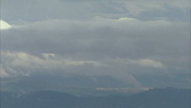 Clouds coming up valley and over mountain ridge time lapse