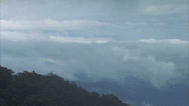 Clouds coming up valley and over mountain ridge time lapse