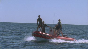 marine scientists on red zodiac inflatable boat heading out across bay pointing at water