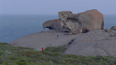 people walking down slopes of remarkable rocks