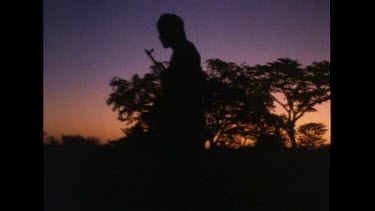 Sunset. Man with automatic rifle in silhouette on guard