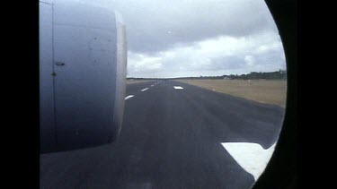 Jet of plane shot through window as plane turns on runway.