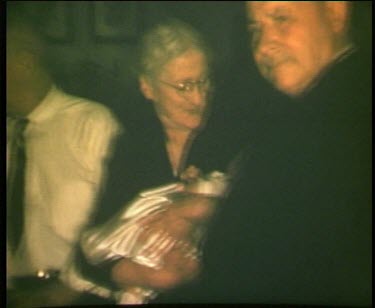 Grandmother with other elderly people hold baby toddler