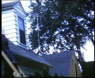 Man on ladder next to his roof