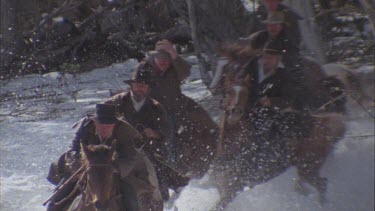 men riding horses over snow covered ground