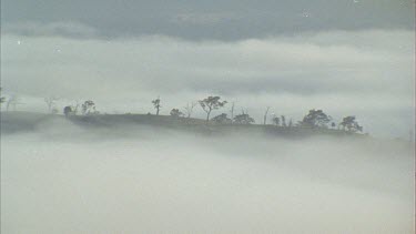 Zoom out from shot of mist shrouded ridge.