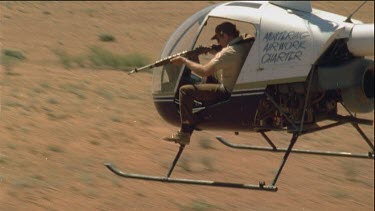 Man in helicopter aiming gun