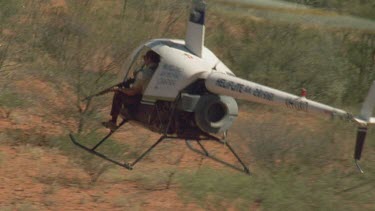 Man in helicopter aiming gun