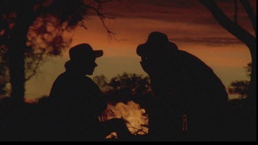 silhouette of two men in front of fire