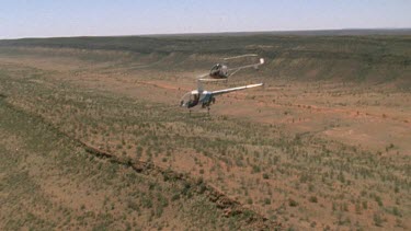 two helicopters flying over desert