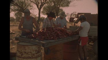 Group Of Men Preparing Meat On A Makeshift Table