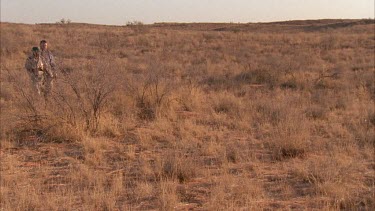 Klaus Kruiper tracker and scientist Louis Liebenberg showing direction of animal walking through grass