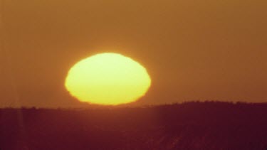 sun coming up over sand dunes and grass tussocks beautiful colours , looks like large golden ball beautiful light