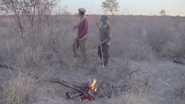 bushmen hunters trying to get warthog out of hole by starting fire