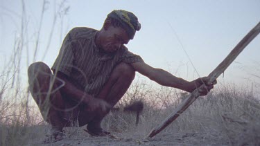 bushmen sharpening spear with crude axe